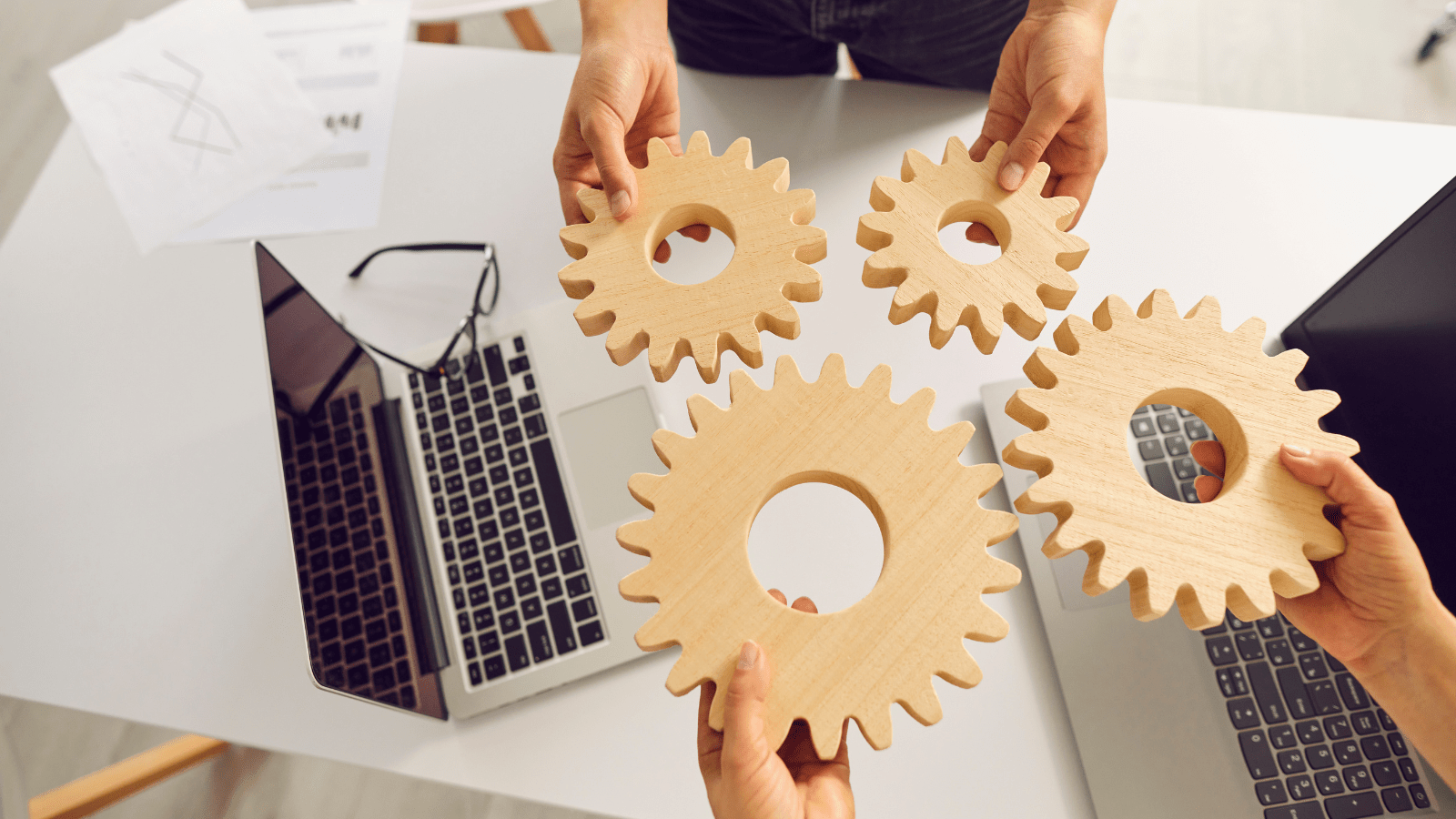 colleagues holding wooden cogs and making them work together