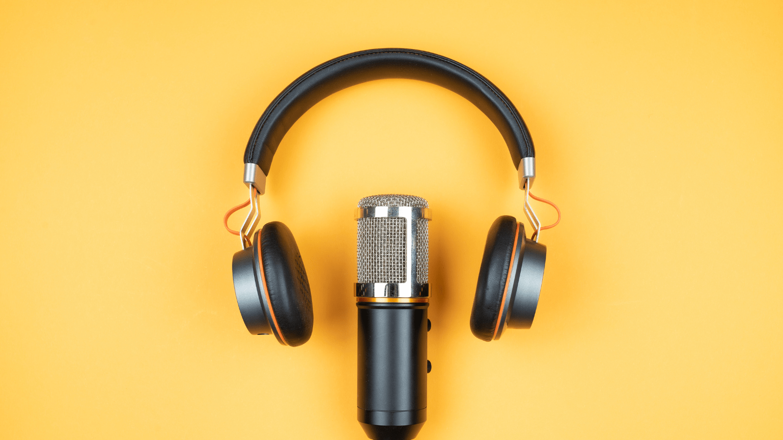 Close-up of a studio microphone with a pair of headphones placed around it, set against a bright yellow background.